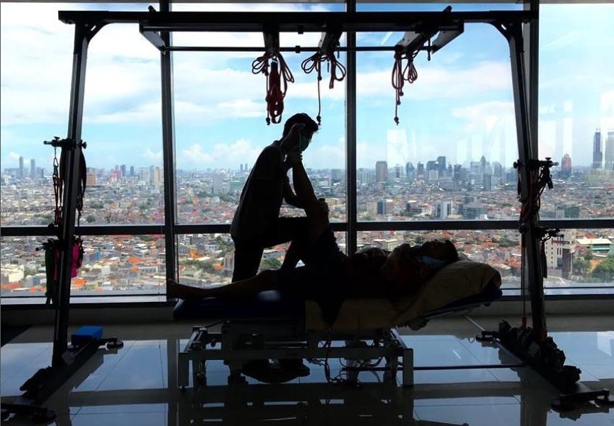 A therapist treating a patient in front of the Jakarta skyline